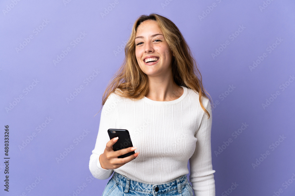 Young blonde woman isolated on purple background using mobile phone Young blonde woman isolated on purple background using mobile phone