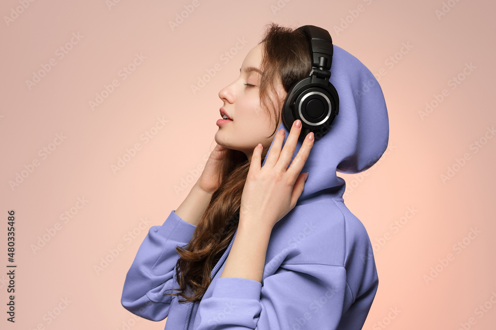 Girl in wireless headphones, face in profile on a soft pink background in a  oversized hoodie. Stock Photo | Adobe Stock