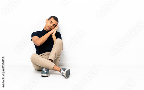 African American man sitting on the floor making sleep gesture in dorable expression