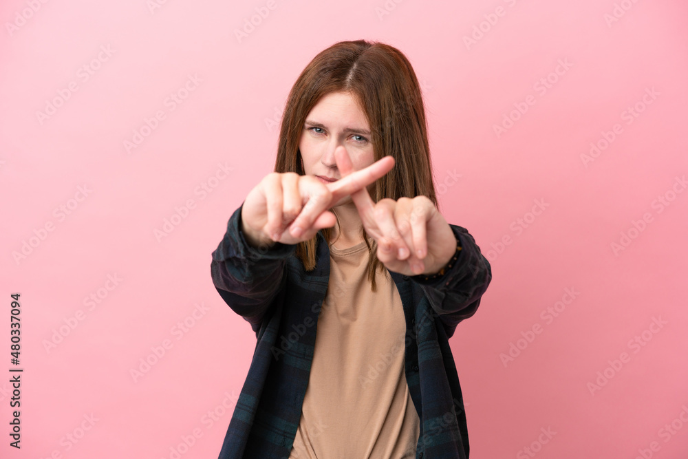 Young English woman isolated on pink background making stop gesture with her hand to stop an act Young English woman isolated on pink background making stop gesture with her hand to stop an act