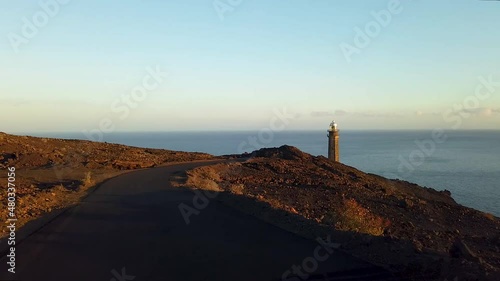 Driving along the road at sunset to the lighthouse towering on the rocky coast of Heirro Island, Faro de la Orchilla photo