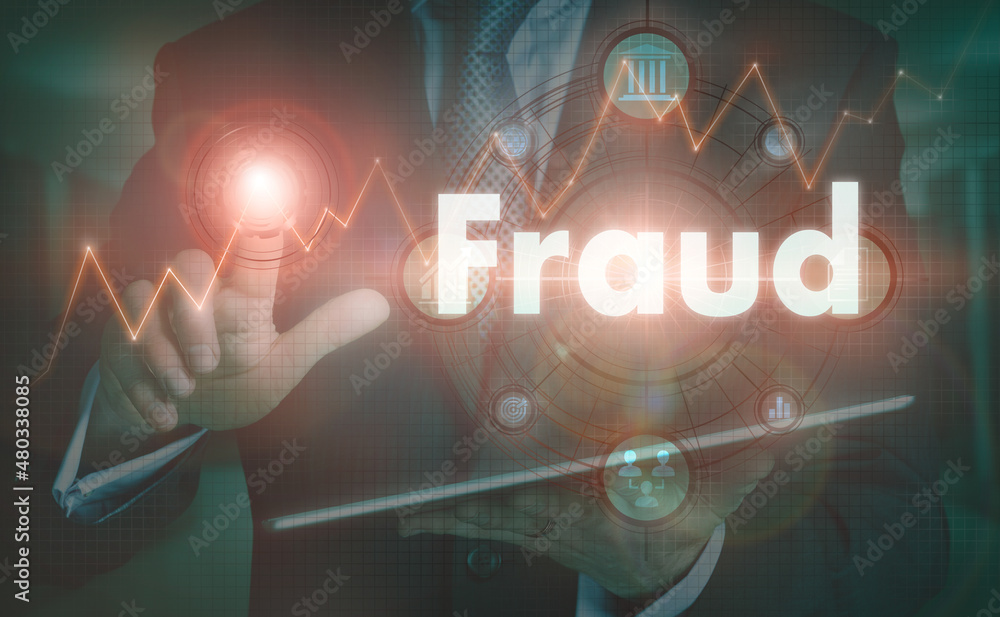 A businessman operating a computer display with a Fraud business word concept on it.