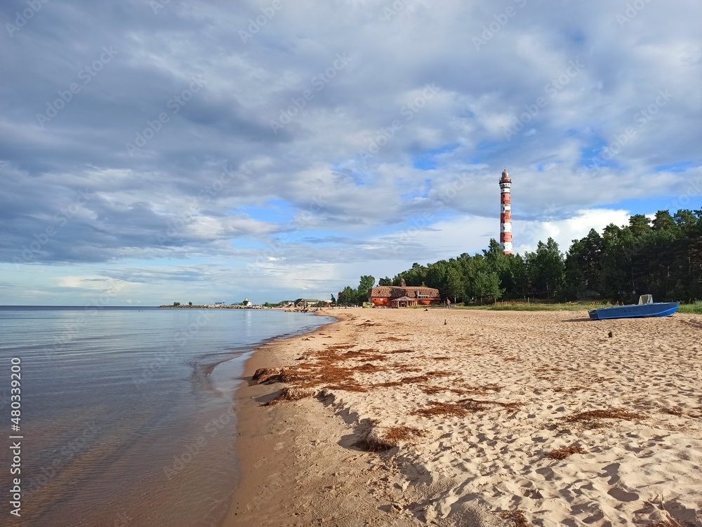 Lighthouse on the sandy shore of the lake on a summer day
