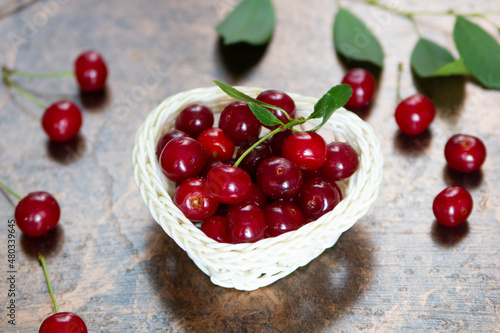 Ripe cherries in a white basket on a brown background.. Close-up. Copyspace.