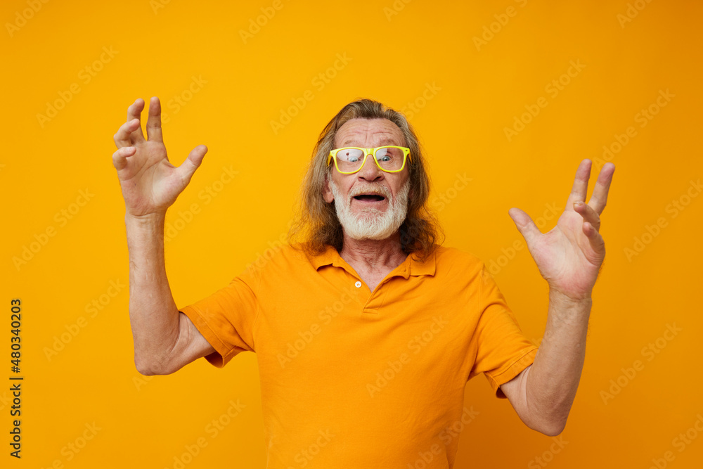 Portrait elderly man yellow t-shirt and glasses posing isolated background