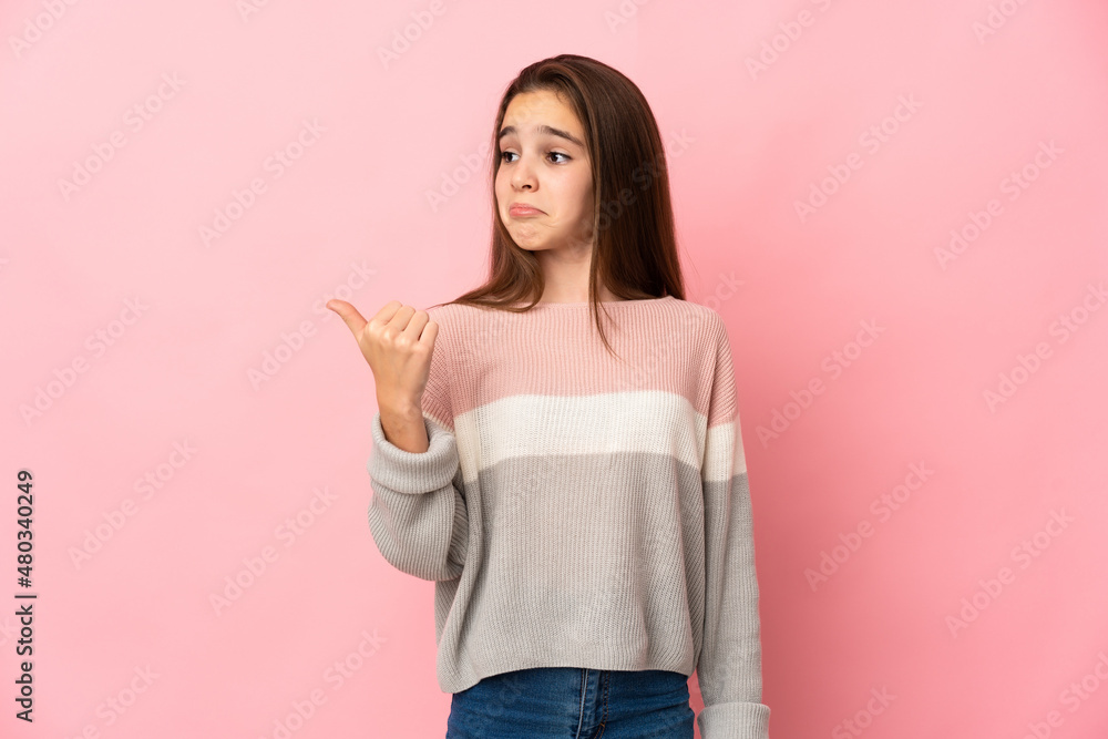 Little girl isolated on pink background unhappy and pointing to the side Little girl isolated on pink background unhappy and pointing to the side