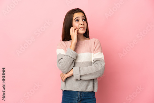 Little girl isolated on pink background is a little bit nervous