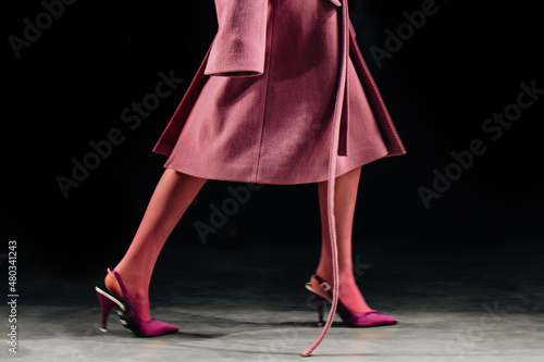 Fotografie Cropped female figure dressed in classic long pink fancy coat and high heels wal