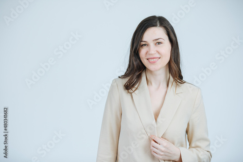 Beautiful woman in a blazer raises her hand in greeting. Welcome new employees to the company. Business woman smiles and shows hand. Warm and cheerful lady boss . Copy space