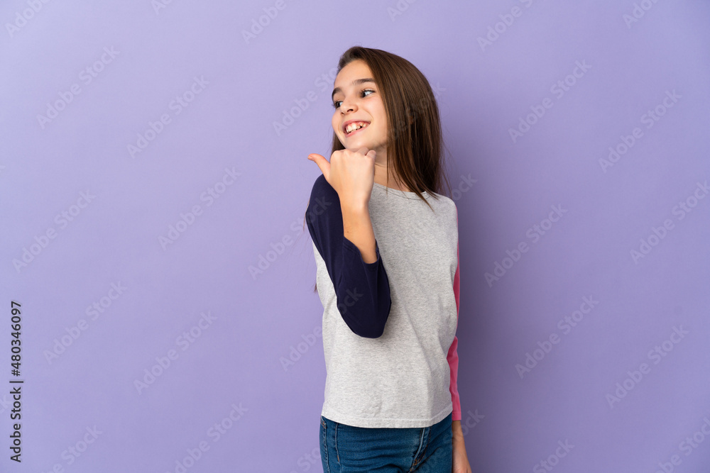 Little girl isolated on purple background pointing to the side to present a product Little girl isolated on purple background pointing to the side to present a product