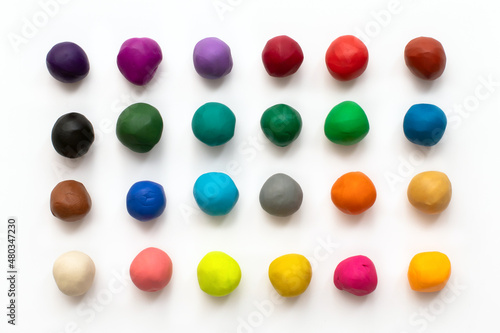 Pieces or balls of Colorful plasticine modelling clay isolated on white background. Top view with shadow. Creativity children toys concept. 24 colors set. photo