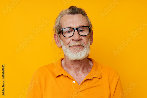 an elderly man with glasses in a yellow t-shirt with glasses close-up