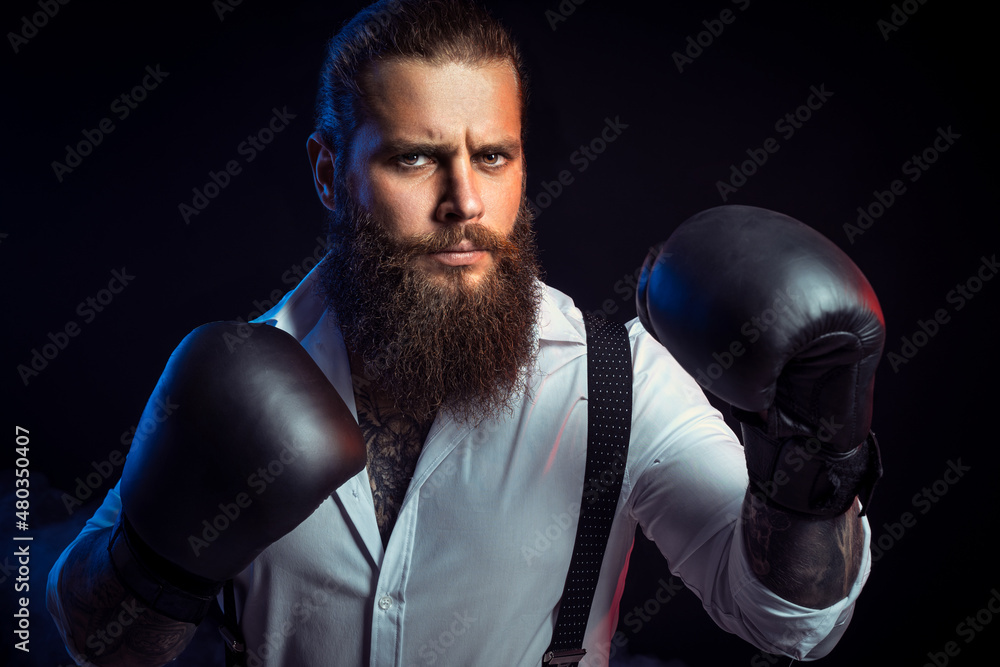 Portrait of bearded man who looking aggressive wears boxing gloves on, white shirt. Man self defense