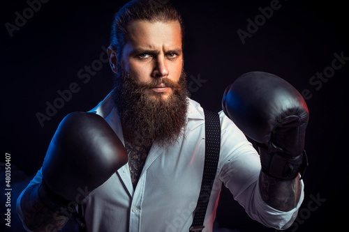 Portrait of bearded man who looking aggressive wears boxing gloves on, white shirt. Man self defense