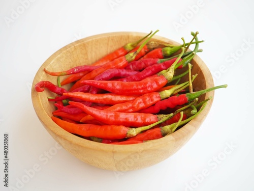 Chili pepper in wooden bowl on white background. closeup photo, blurred.