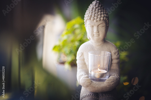 Zen spiritual ritual meditating white face of Buddha  white candle on green floral background. Religion concept  esoterics. Still life style. Home decor. Place for text  copy space.