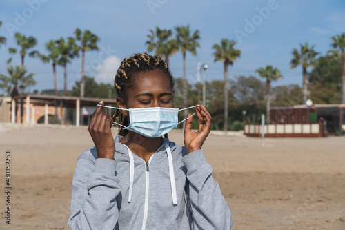Close-up of a young African woman removing her mask on the beach.