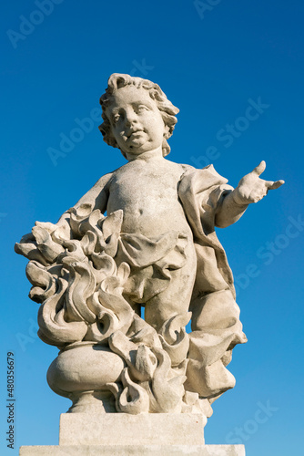 Putto angel statue in white stone against blue sky  symbolic sculpture with flame