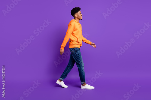 Full length body size profile side view of attractive cheerful guy strolling isolated over bright violet purple color background © deagreez