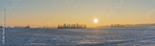 Winter landscape in snow nature with sun, field and trees. Magical winter sunset in a snow field.