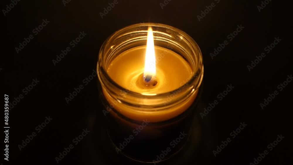 Burning candle in beeswax glass and dimming effect Burning candle in beeswax glass and dimming effect