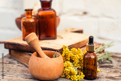 immortelle ,Curry Plant, Herb of St. John, Immortelle and botanically, Helichrysum arenarium. Helichrysum arenarium near glass apothecary bottles for essential oil. Making elixirs for beauty salons photo