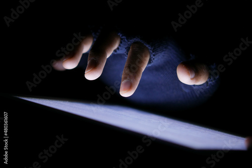 Close up of hacker hand stealing data from digital tablet 