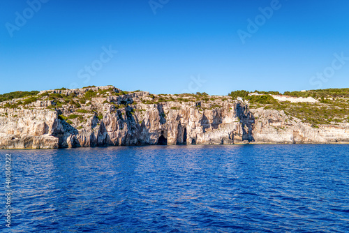 Plant-covered hill with rocks on shore of Corfu island