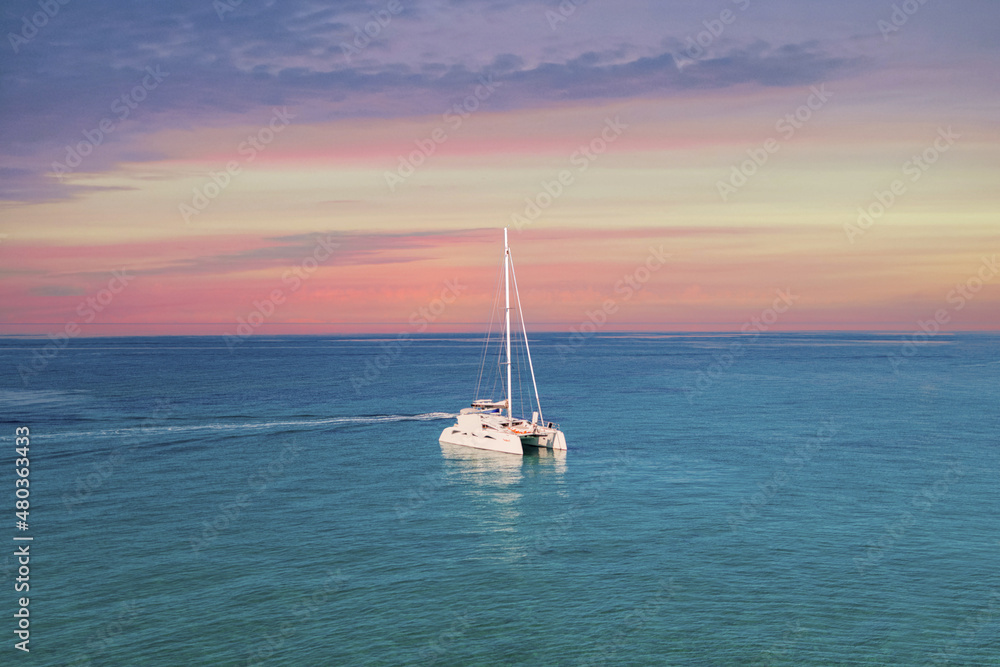 Fototapeta premium Yacht drifting on sea surface under blue cloudless sky