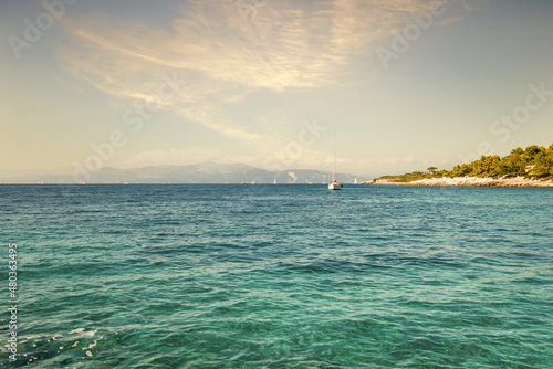 Anchored boat on sea surface against Corfu under blue sky © YouraPechkin