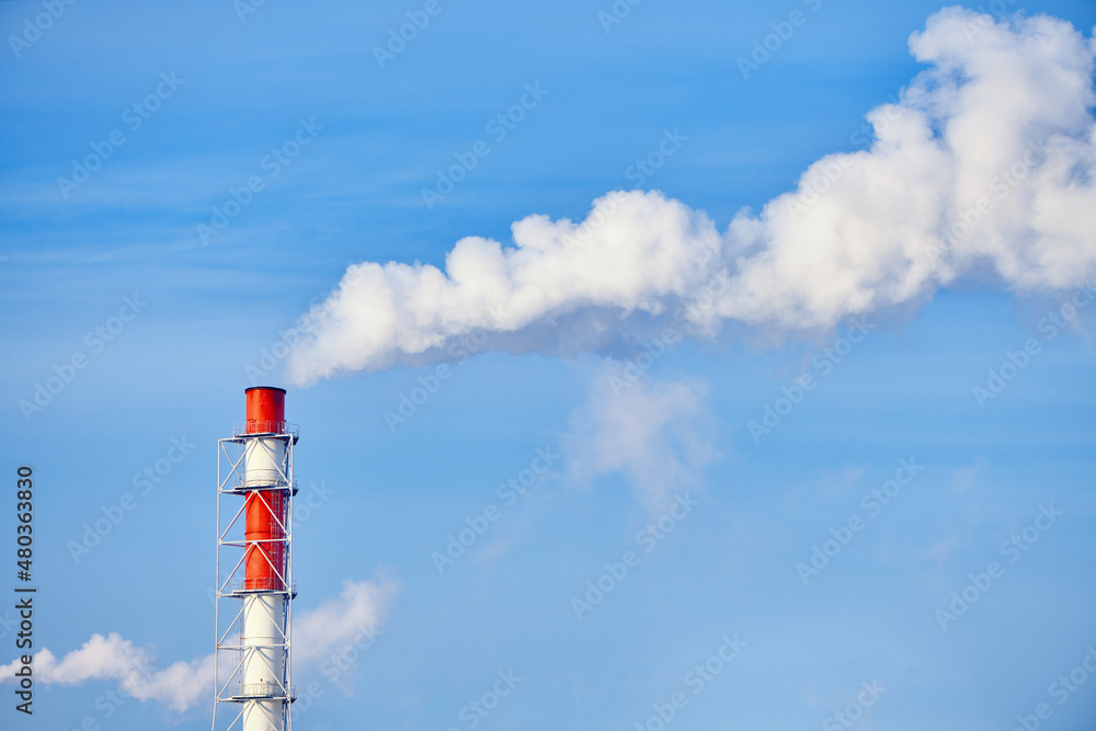 Obraz premium Smoke exhausting from chimney. Huge smoke from the pipe. Red-white chimney of factory. Environmental pollution. Carbon dioxide emissions. Global climate protection concept.