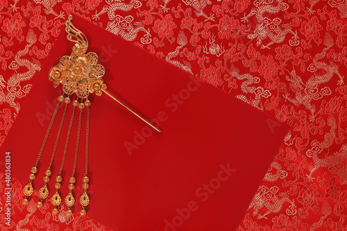 Red fabric with dragon pattern with red copy space for text and golden female hairpin. Concept of Chinese New year and wedding.