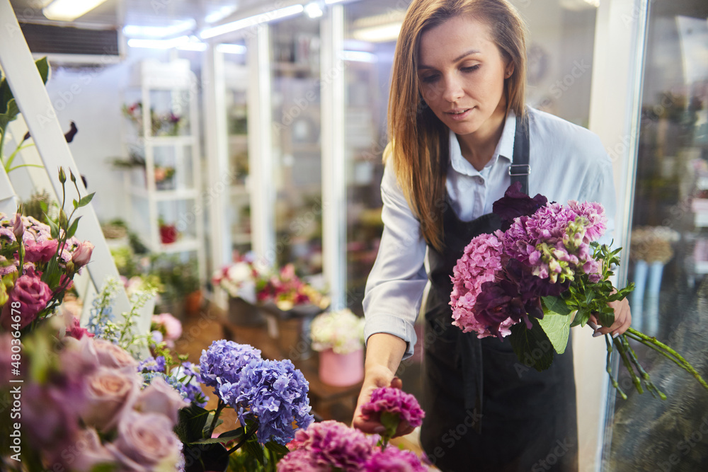 Female florist selecting fresh flowers for bouquet