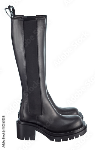 Beautiful pair of modern trendy high black demi-season leather boots with elastic band, with a massive sole, isolated on a white background. Side view.