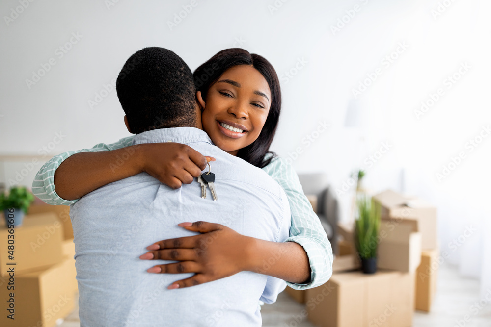 House ownership. Smiling black lady holding house key and hugging her