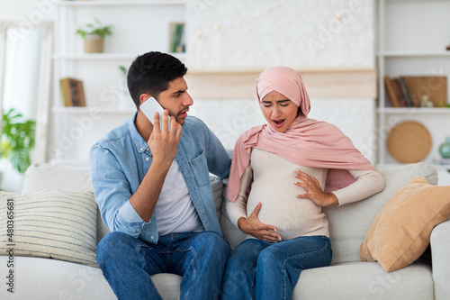 Canvas Print Worried arab husband calling doctor or ambulance while his pregnant wife having
