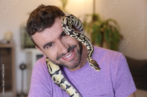 Cute man holding exotic ball python 