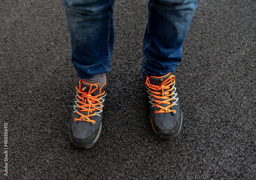 Kid's feet in trekking shoes with bright orange shoelaces