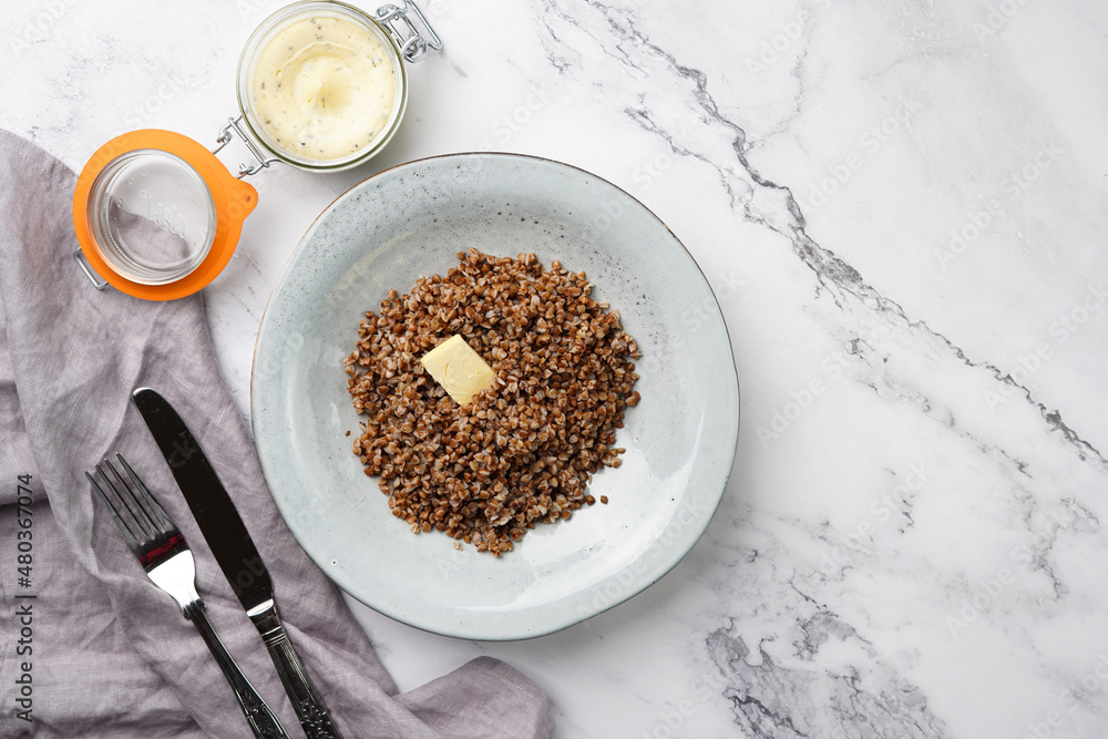 grey porcelain scandi soup bowl with traditional east european dish buckwheat with butter on a marble surface and kitchen towel, top view, copy space grey porcelain scandi soup bowl with traditional east european dish buckwheat with butter on a marble surface and kitchen towel, top view, copy space