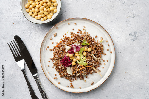 grey porcelain scandi plate with traditional east european dish buckwheat salad with butter and chickpeas on concrete surface, top view