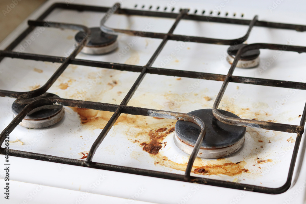 Dirty gas stove with food debris and grease stains. A dirty gas stove