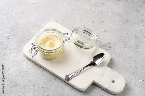 Mason jar with tasty herb butter with grated truffles on marble board on grey concrete surface © Romana