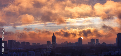 The city smog is illuminated by the rays of the rising sun in the early morning.