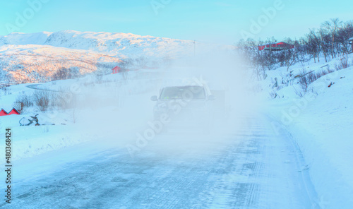 SUV rides on a winter forest road - A car in a snow-covered road among trees and snow hills - Tromso, Norway