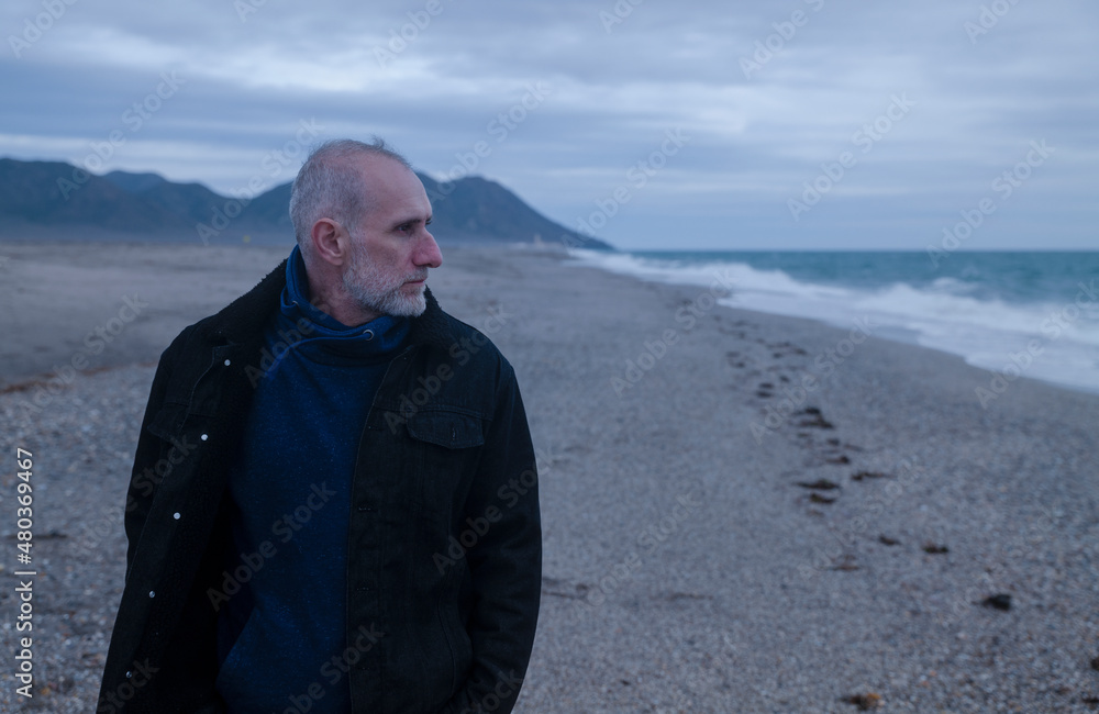 Adult man in winter clothes on beach during sunset. Almeria, Spain