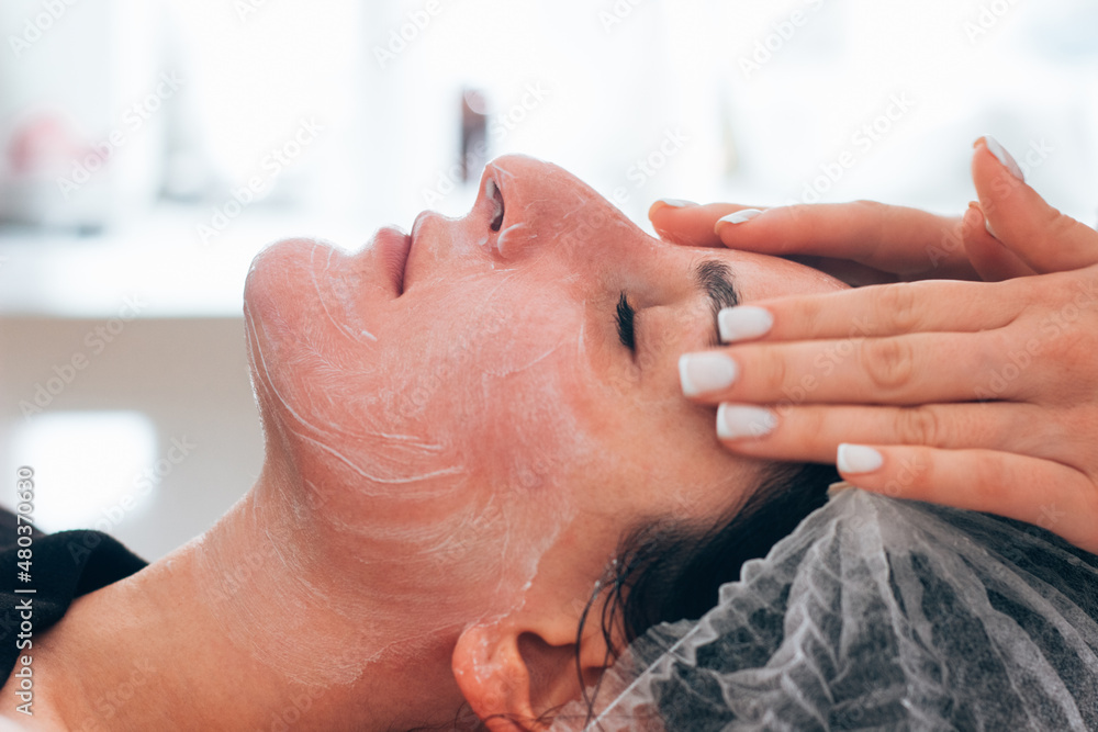 At the reception of the cosmetologist, the doctor massages the face of a satisfied client after the cream, At the reception of the cosmetologist, the doctor massages the face of a satisfied client after the cream,