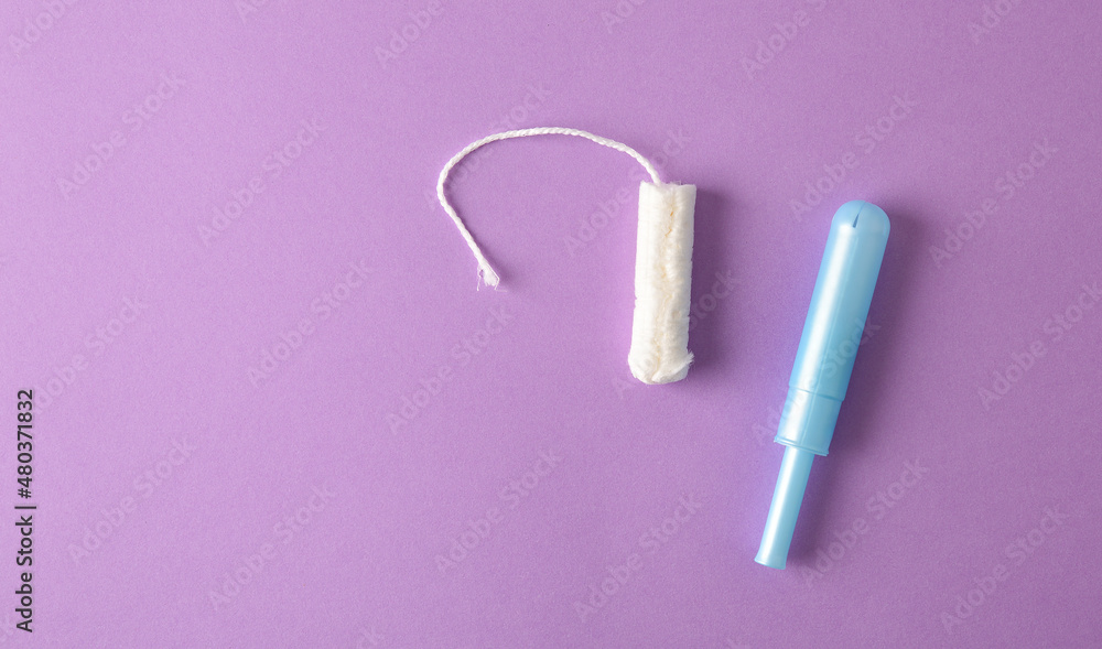 Absorbent protective tampon for women care on lilac background Absorbent protective tampon for women care on lilac background