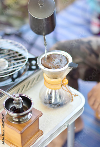 Brewing coffee drip. Pouring hot water for drink to coffee drip in camp site. Coffee drift with camping concept.