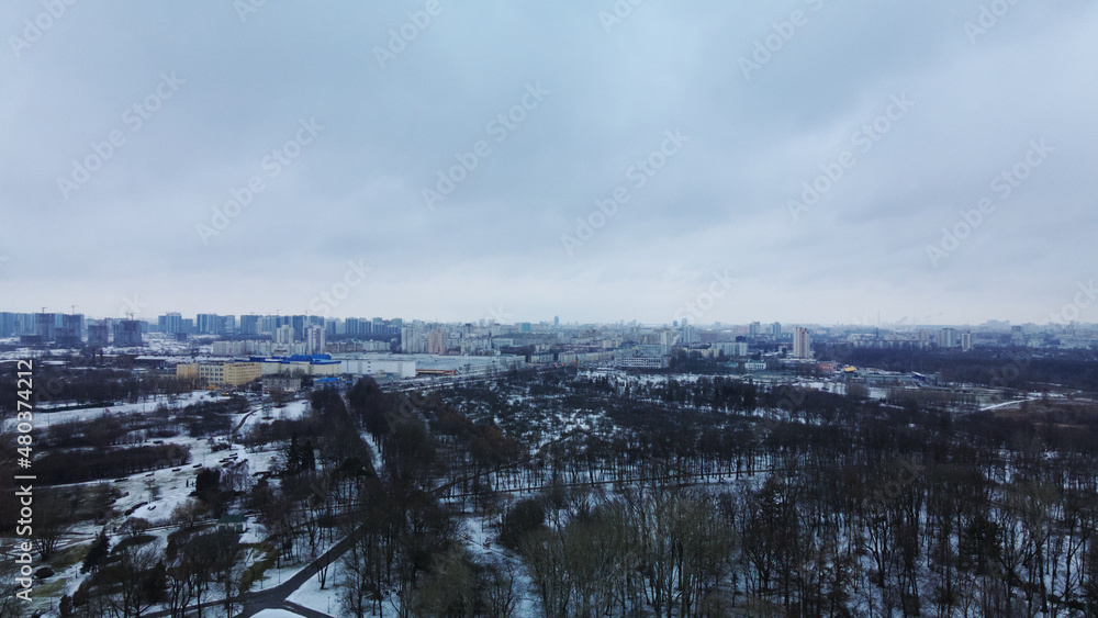 Flying in a suburban park. City blocks are visible. Winter cityscape. Aerial photography.