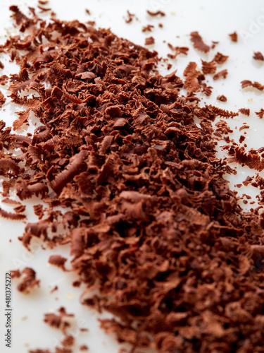 Dark chocolate pieces isolated on white background. Chocolate bar chunks, shavings and cocoa crumbs Top view.